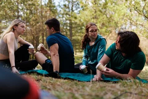 Group of friends enjoying coffee while camping in the woods on a sunny day Stock Photos