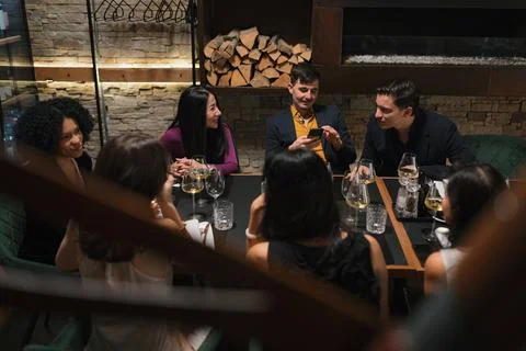 Group of friends enjoying dinner and conversation at a restaurant gathering Stock Photos