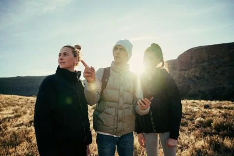 Group of friends finding directions while hiking through mountain at sunset Stock Photos