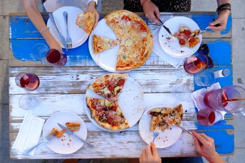Group of friends having dinner at table with pizza Stock Photos