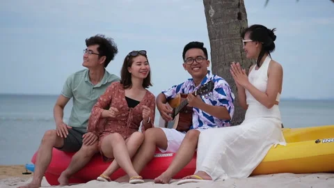 Group of friends having fun on the beach with guitar and singing songs Stock Footage 152967410