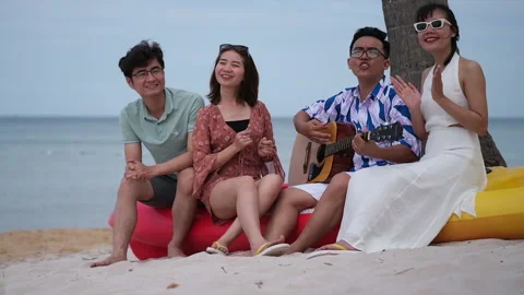 Group of friends having fun on the beach with guitar and singing songs Stock Footage 152967421