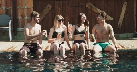 Group of friends having fun at pool. People cheers drinking summer cocktails at Video stock 158217245