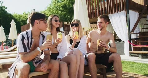 Group of friends having fun at pool. People cheers drinking summer cocktails at Stock Footage 158369326