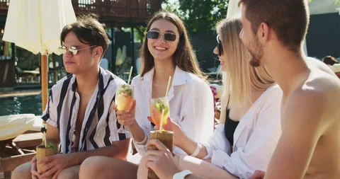 Group of friends having fun at pool. People cheers drinking summer cocktails at Video stock 158369673