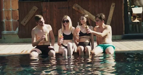 Group of friends having fun at pool. People cheers drinking summer cocktails at Stock Footage 158374954