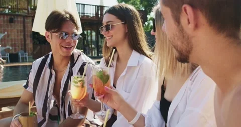 Group of friends having fun at pool. People cheers drinking summer cocktails at Stock Footage 158479595