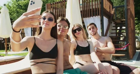 Group of friends having fun at pool. Taking selfie on smartphone sitting Stock Footage 158481428