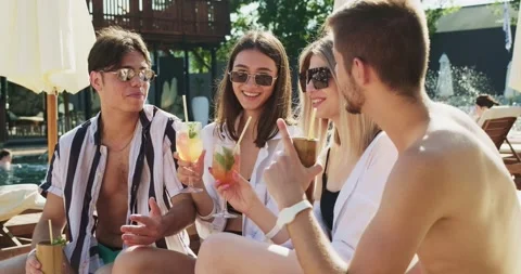 Group of friends having fun at pool. People cheers drinking summer cocktails at Video stock 158566174