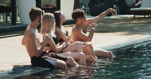 Group of friends having fun at pool. Taking selfie on smartphone sitting Stock Footage 158569796