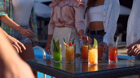 Group of friends having fun at poolside summer party taking colorful cocktails Stock Footage 129091856