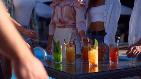 Group of friends having fun at poolside summer party taking colorful cocktails Stock Footage 129598872