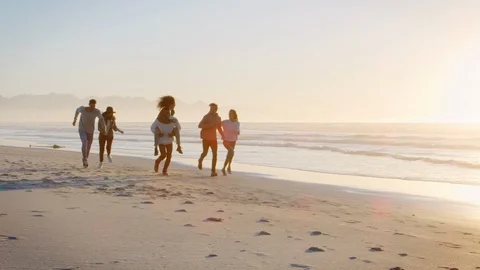 Group Of Friends Having Fun Running Along Winter Beach Together Stock Footage 90202753