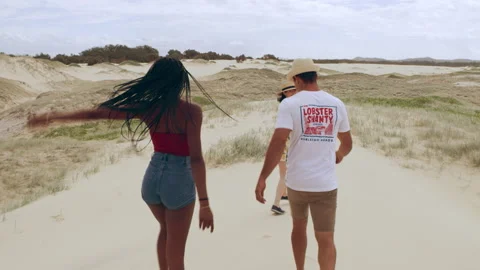 Group of friends having fun walking along sand dunes towards the beach in Austra Video stock 199459038