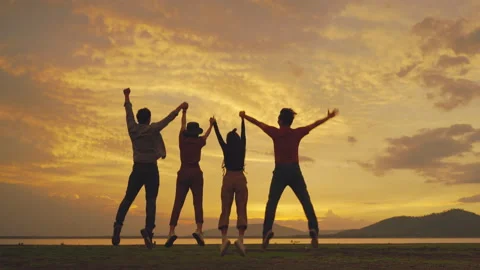 Group of friends jumping cheerfully during a walk in the setting evening Stock Footage 156251244