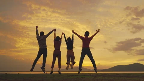 Group of friends jumping cheerfully during a walk in the setting evening Stock Footage 157133565