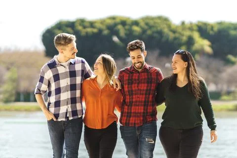 Group of friends laughing while strolling near a river Stock Photos