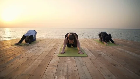Group of friends leans down doing an exercise on the beach slow motion Video stock 75572125