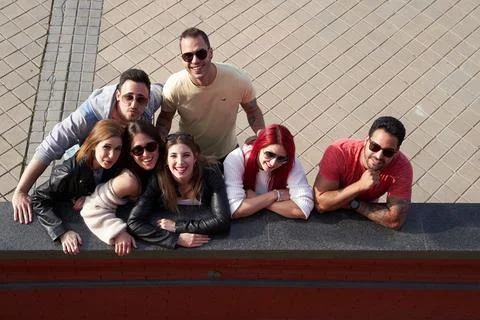 Group of friends looking up and smiling at camera while standing together 스톡 사진