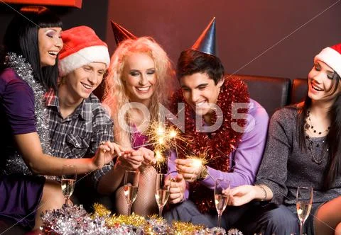 Group of friends looking at sparkling bengal lights and laughing Stock Photos