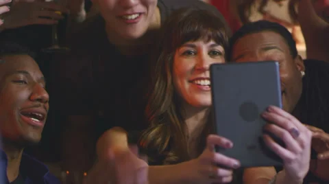 A group of friends at a party use a tablet to take pictures of themselves Stock Footage 34015997