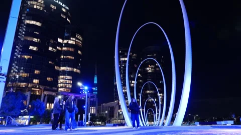 A group of friends pass Arches of Spanda Sculpture at night in Perth Aus 6K Stock Footage 311612912