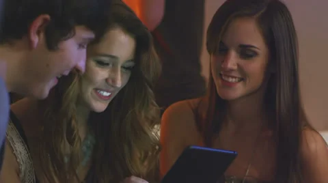 A group of friends play with a tablet while hanging out at a house party Stock Footage 34016015