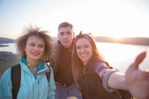 Group of friends resting on mountain while hiking. Hikers relaxing and taking Foto stock