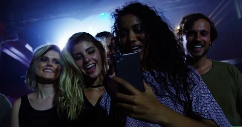 Group of friends reviewing pictures on mobile phone at a concert 4k Stock Footage