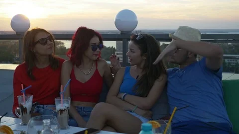 Group of friends on a rooftop bar having a chat and enjoying a drink Stock Footage 71383767
