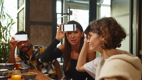 Group of friends sit in a cafe, play in word game with phones, girl explain a Stock Footage 121939449