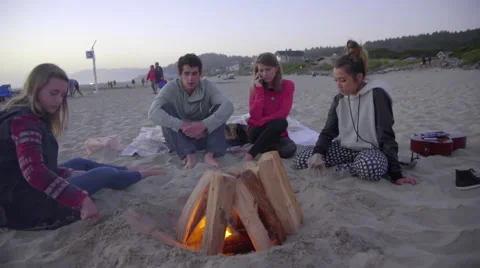 Group of friends sit by fire together Stock Footage 53232956