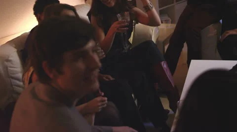 A group of friends sit together on a couch and chat during a house party Video stock 34016138