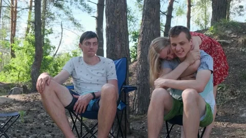 Group of friends sitting on chairs in a pine forest and communicate. 動画素材 135080137