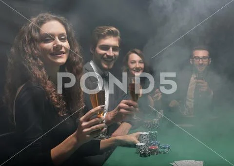 Group of friends sitting at game table in casino Stock Photos