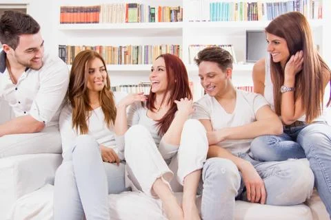 Group of friends sitting on sofa talking and smiling Stock Photos