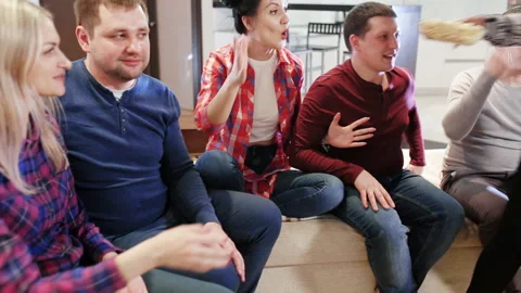 Group of friends sitting on the sofa, watching TV and laughing Stock Footage 88174057