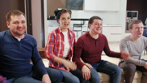 Group of friends sitting on the sofa, watching TV and laughing Video stock 95645924