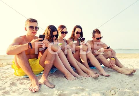 Group of friends with smartphones on beach Stock Photos