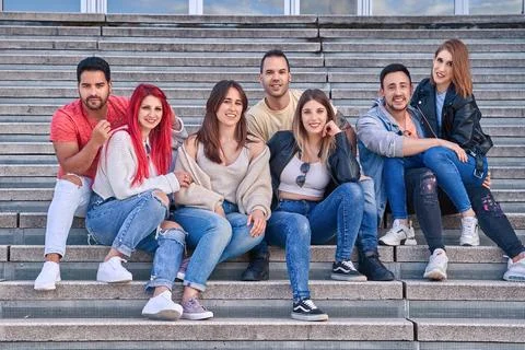 Group of friends smiling at the camera while sitting together on outdoor stairs. 스톡 사진