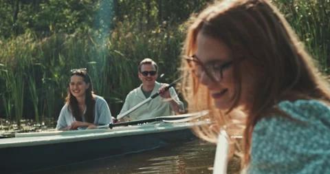 Group of friends smiling while paddling in canoes Stock Footage 221319110