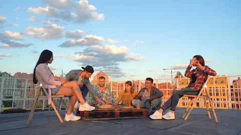 Group of friends spending time together. Sitting at the roof, smiling, joking. Stock Footage 110700117