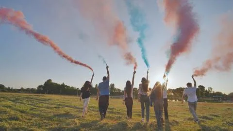 A group of friends spraying multi-colored smoke at sunset. Stock Photos
