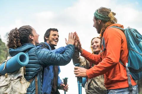 Group of friends stacking hands on peak of mountain Foto stock