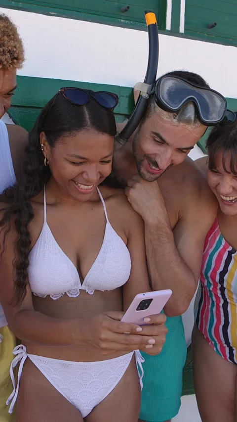 Group of friends using mobile phone at the beach. Stock Footage 277468093