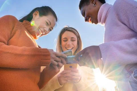 Group of friends using mobile phone sharing content on social media. Gaming and Stock Photos