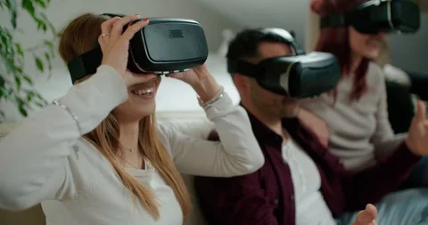 Group of friends using virtual reality simulator glasses in living room. Shot in Stock Footage 117182326