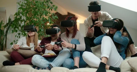 Group of friends using virtual reality simulator glasses in living room. Shot in Stock Footage 117182608