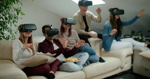 Group of friends using virtual reality simulator glasses in living room. Shot in Stock Footage 117182610