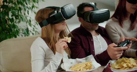 Group of friends using virtual reality simulator glasses in living room. Shot in Stock Footage 117182808